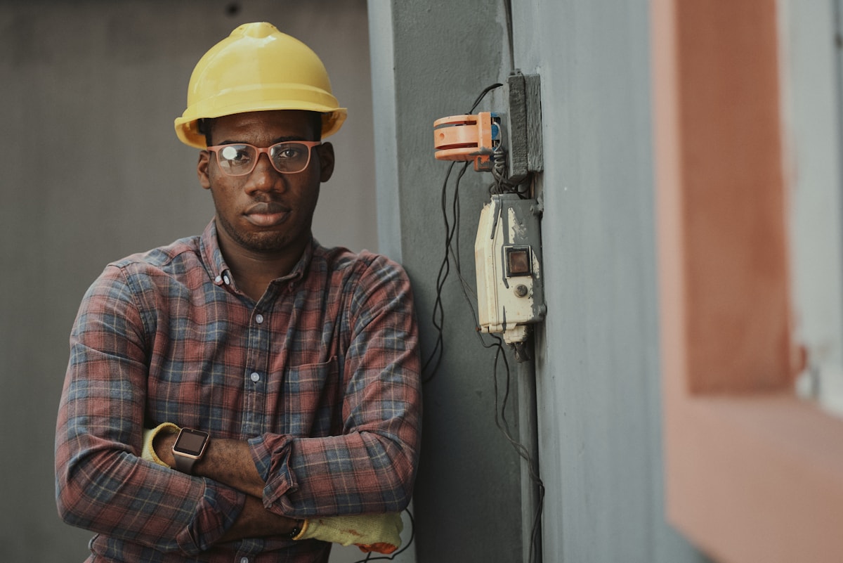 Tradesperson wearing a hard hat beside electrical controls